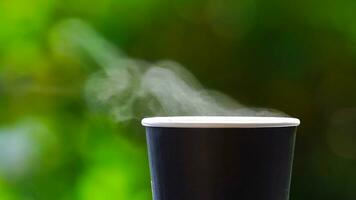 coffee takeaway in a paper cup on top of the car roof green tree background at sunrise in the morning,  selective focus, soft focus. photo