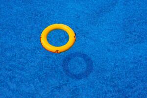 Top view of lifebuoy floating in blue swimming pool, soft focus. photo