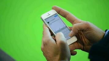 gens l'écriture une message dans mobile Téléphone avec vert ou chrominance Contexte video
