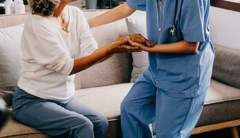 contento joven hembra enfermero proporcionar cuidado médico Servicio ayuda apoyo sonriente antiguo abuela a cuidados en el hogar médico visita, dama cuidador médico dar empatía animar retirado paciente sentar en sofá a hogar hospital foto