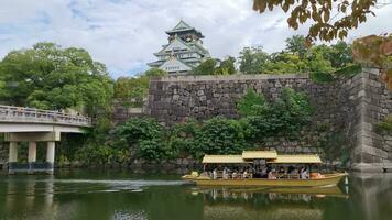 Osaka, Japan on 8 October 2023.  Osaka Castle on a sunny summer day, with clear blue skies and white clouds. The castle is one of Japan's most famous landmarks. With a tourist boat on the river video