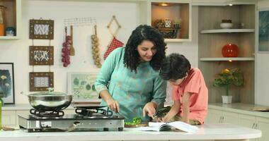 video di madre cucinando nel cucina e figlio fare compiti a casa