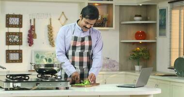 Happy woman watching video recipe on laptop while cooking  healthy lunch in kitchen using laptop