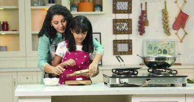 vidéo de Indien mère enseignement sa fille en train de préparer chapati dans une cuisine video