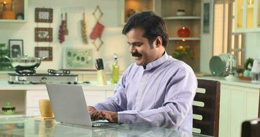 Video of Man Sitting At The Kitchen Table Working From Home On Laptop