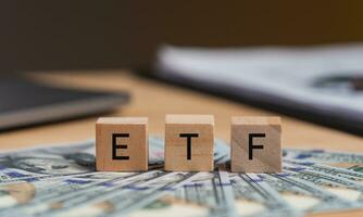 Concept words ETF on wooden blocks, acronym ETF which refers to Exchange Traded Fund inscribed on wooden cubes United States dollars. Economy and investments. photo