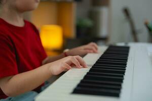 cerca arriba mano, contento pequeño asiático linda bebé niña sonrisa jugando aprendizaje en línea piano música en vivo habitación a hogar. el idea de ocupaciones para niño a hogar durante cuarentena. música aprendizaje estudiar. foto