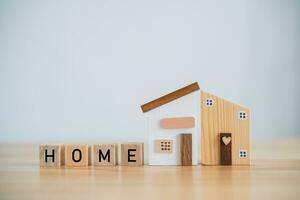 Model house and wood blocks with word HOME wood on table. plan finances investments and savings to buy house real estate.Home on table business accounting and tax and insurance concept. photo