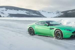 un aston martín ventaja verde en un hielo la carretera en montañoso areas generado por ai foto