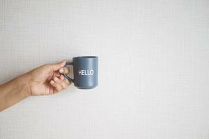 hand holding a blue coffee cup with hello word photo