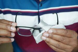 cleaning eyeglass with tissue close up photo