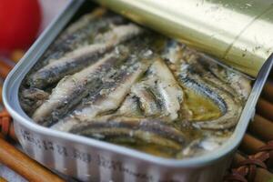 open tin of sardines on white tiles background. photo