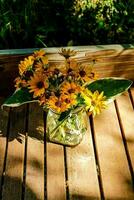 a vase of flowers sitting on a wooden table photo