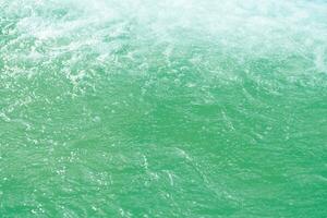 Defocus blurred transparent blue colored clear calm water surface texture with splashes and bubbles. Trendy abstract nature background. Water waves in sunlight with copy space. Blue watercolor shining photo