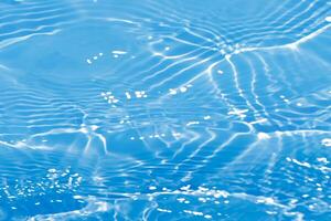 Defocus blurred transparent blue colored clear calm water surface texture with splashes reflection. Trendy abstract nature background. Water waves in sunlight with copy space. Blue watercolor shine. photo