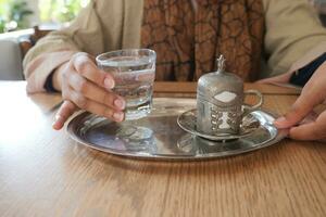 un taza de turco café y vaso de agua en mesa foto