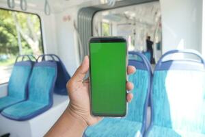 young man hand using smart phone with green screen inside of metro train photo