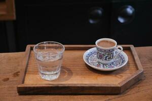 un taza de turco café y vaso de agua en mesa foto
