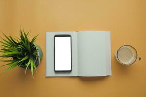 top view of smart phone with empty screen and notepad on table photo