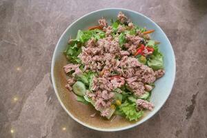 spoon pick tuna salad from a bowl on table photo