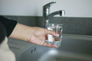 agua torrencial desde un grifo grifo en un vaso, Bebiendo puro agua concepto foto