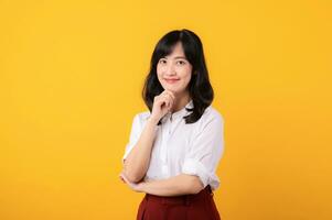 retrato joven hermosa asiático mujer emprendedor contento sonrisa vestido en blanco camisa y rojo plantas demostración pensando gesto aislado en amarillo estudio antecedentes. foto