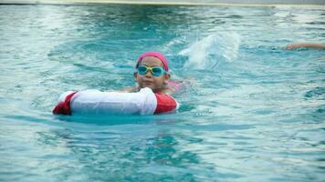 Little girl plays in the outdoor swimming pool of tropical resort during family summer vacation. Kids learning to swim. Healthy Summer Activities for Kids. video