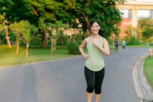 Fit Asian young woman jogging in park smiling happy running and enjoying a healthy outdoor lifestyle. Female jogger. Fitness runner girl in public park. healthy lifestyle and wellness being concept photo