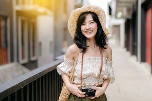 Happy youth asian woman with camera travels street city trip on leisure weekend. Young hipster female tourist sightseeing summer urban Bangkok destination. Asia summer tourism concept. photo