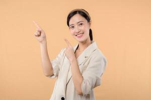 Studio portrait of happy successful confident young asian business woman. Beautiful young lady in white jacket smiling at camera standing isolated on solid beige colour copyspace background photo