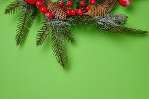 Christmas wreath made of fir branches and other decorations on a green background, copy space photo