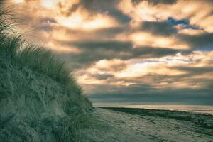 on the beach with dune on the Baltic Sea. Cloudy sky. Waves meet sand. Landscape photo