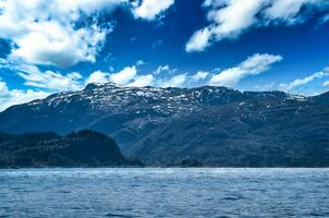 Fjord with mountains on horizon. Water glistens in the sun in Norway. Landscape photo