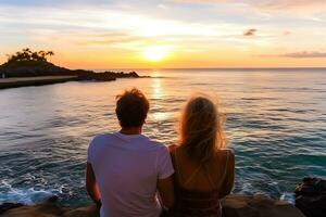 Caucasian couple sitting on rock near sea at sunset photo
