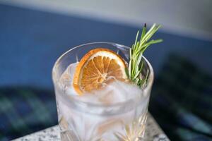 Glass of gin tonic cocktail with rosemary and orange. Copy space photo