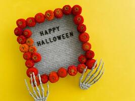 The paws of the skeleton hold a frame with the inscription - happy Halloween photo