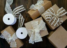 On a wooden table there are craft boxes decorated with bows photo