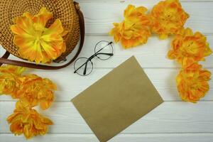 On the wooden table there is a craft envelope with a letter and yellow tulips photo