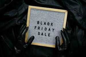 Hands in black gloves hold a frame with the inscription Black Friday sale photo