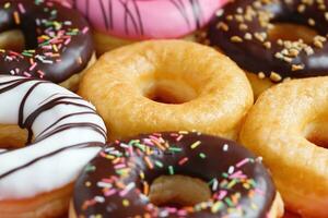 assorted donuts with chocolate frosting, topping sprinkles donuts Colorful variety and Variety of flavors mix of multi colored sweet donuts with frosted sprinkled on pink background. top view photo