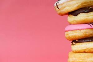 clasificado rosquillas con chocolate Crema, Adición asperja rosquillas vistoso variedad y variedad de sabores mezcla de multi de colores dulce rosquillas con escarchado rociado en rosado antecedentes. parte superior ver foto