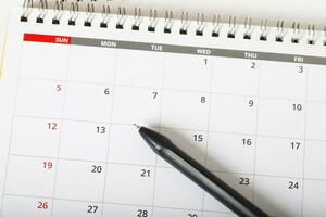 el calendario del mes calendario para hacer una reunión de citas o administrar el horario cada día y colocar un bolígrafo sobre fondo amarillo para planificar el trabajo y el concepto de viaje. foto