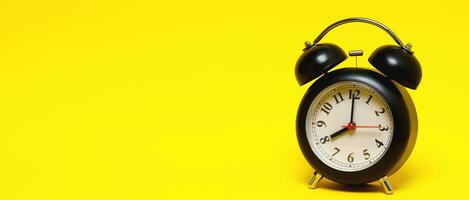 vintage retro alarm clock eight minutes to twelve time o'clock on  yellow background. photo