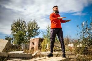 Adult man is exercising outdoor on sunny day. He is stretching his body. photo