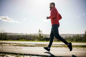 adulto hombre es trotar al aire libre en soleado día. foto