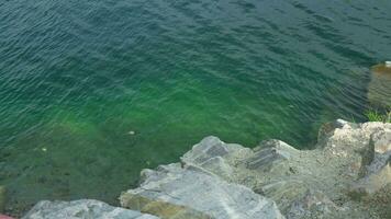 chiaro azzurro acqua, roccioso riva con grande granito pietre. video