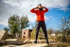 Adult man is exercising outdoor on sunny day. He is stretching his body. photo