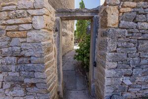 View through an old stone door frame without a door into a backyard of an ancient building photo