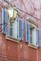 Image of a facade of an antique house with windows with blue shutters and a historic street lamp photo