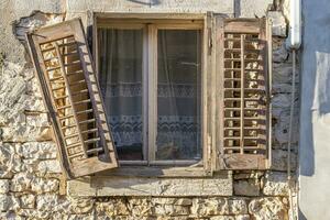 imagen de un antiguo ventana con un dañado obturador en un antiguo Roca casa foto